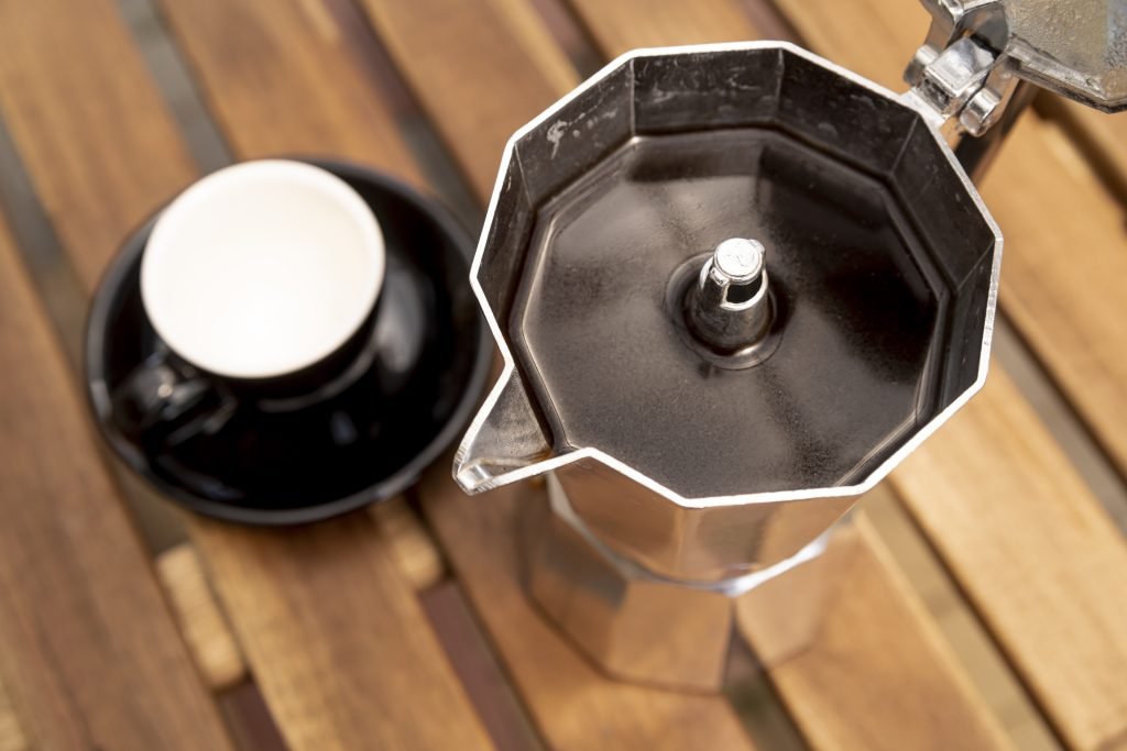 Vista superior de uma cafeteira italiana cheia de café. A moka pode ser utilizada para preparar café espresso em casa. Imagem de Freepik.